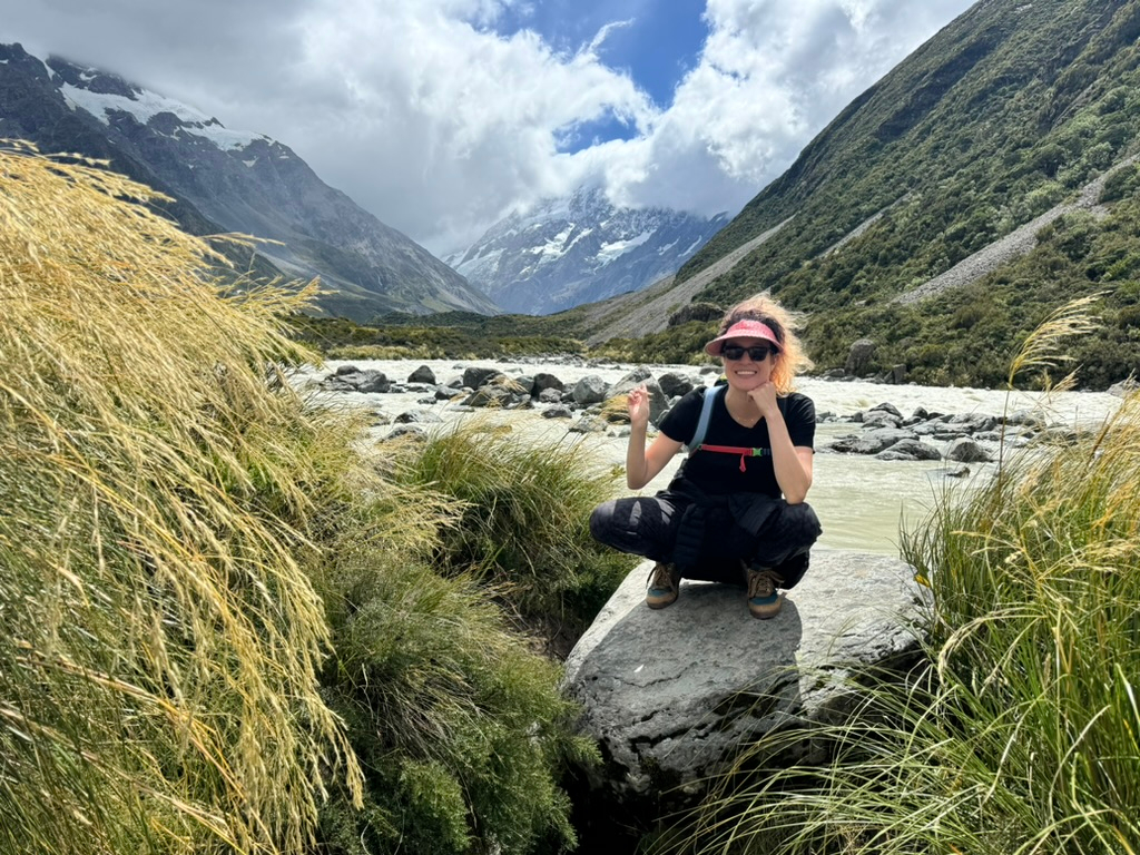 A woman pointing to the scenery on the Hooker Valley Track in New Zealand