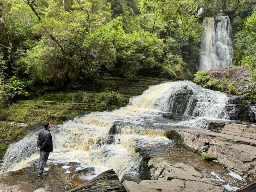 A man admiring McLean Falls in Catlins Forest Park, New Zealand