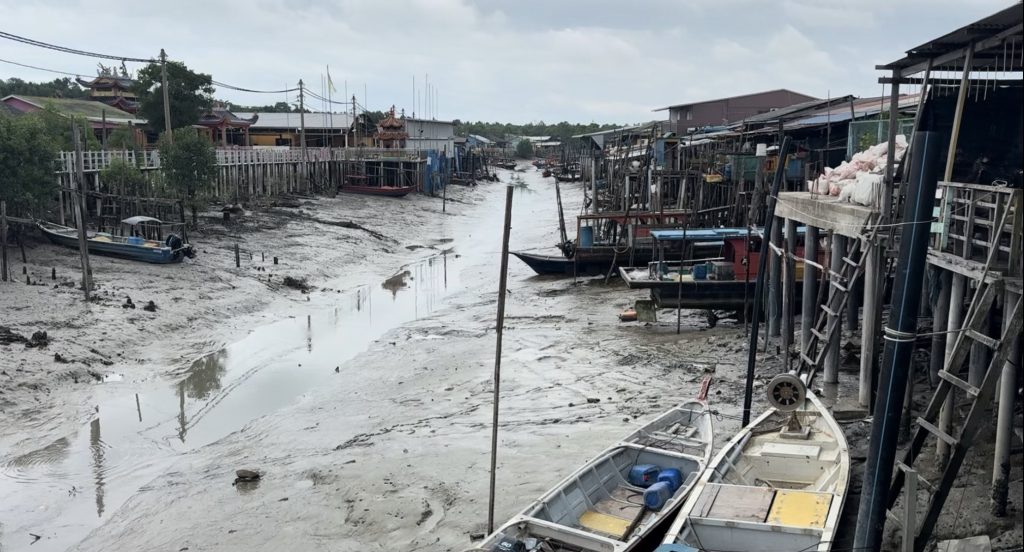 Boats beached and buildings on stilts while tide is out on Crab Island, Malaysia