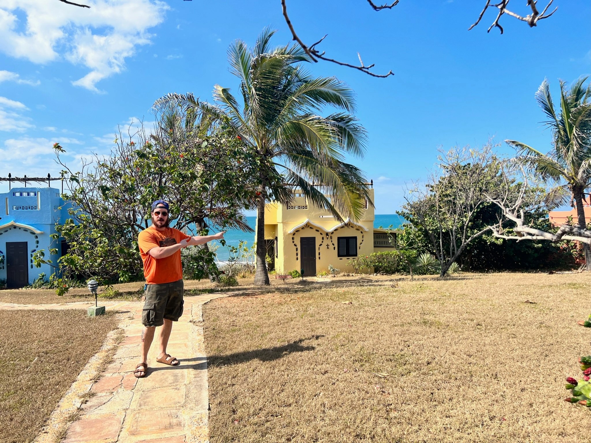 A man pointing to a yellow beach bungalow at Jakes Resort in Treasure Beach, Jamaica