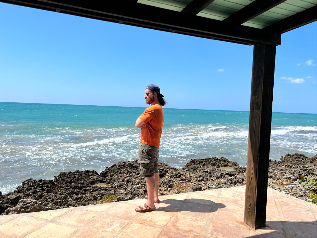 A man with his arms crossed admiring ocean views on a villa deck at Jakes in Treasure Beach, Jamaica