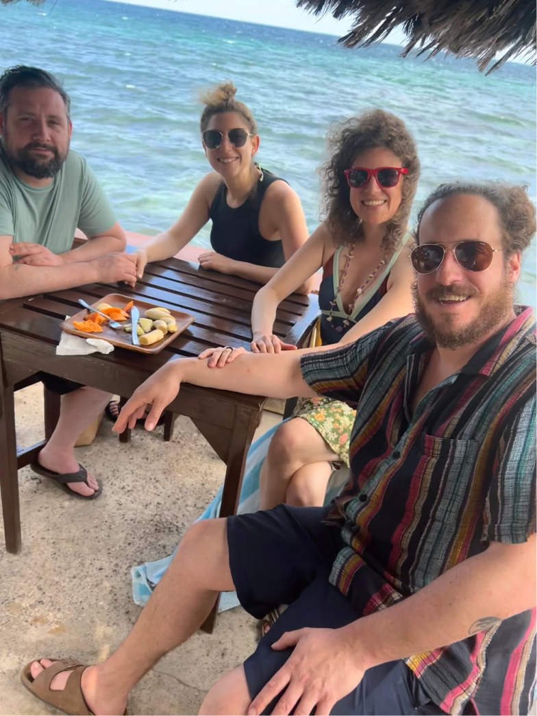 2 couples enjoying a fruit platter on vacation in Negril, Jamaica with ocean views behind them