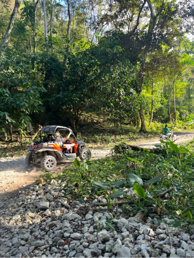 A distant view of a couple in a 4-wheeler amidst Jamaica's scenery