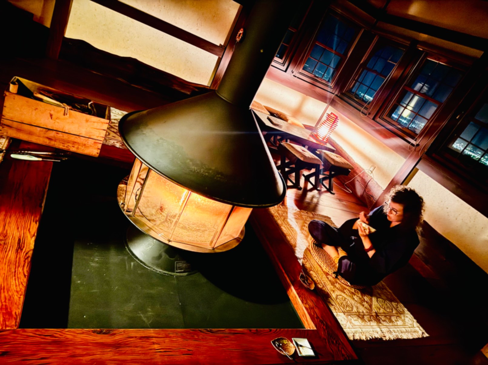 Woman eating Japanese dessert in front of indoor wood-burning stove at Ikumo Lodge in Komatsu, Japan