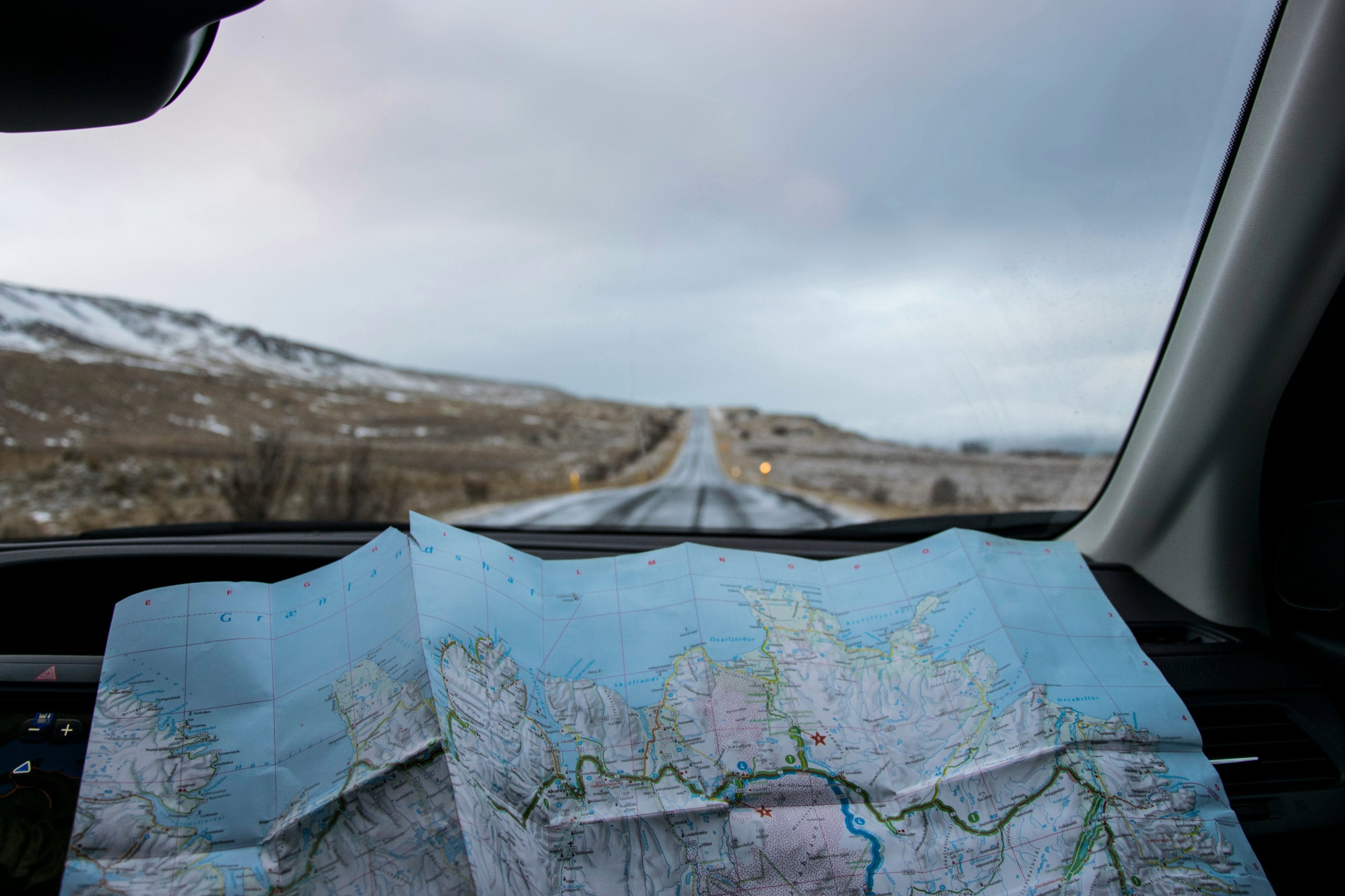 An open map in a car with an open road out the front window