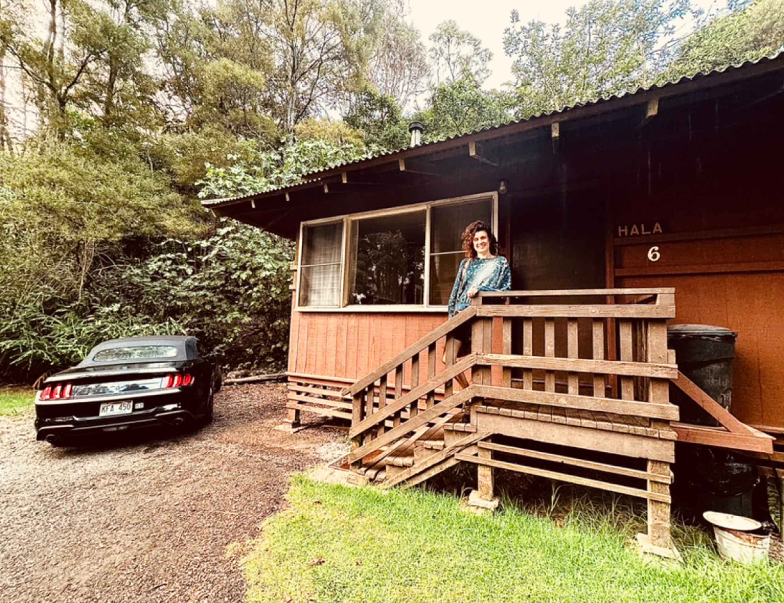 Ford Mustang Convertible and woman in front of The Cabins at Kokee, a remote accommodation in Kokee State Park, Kauai, Hawaii, USA