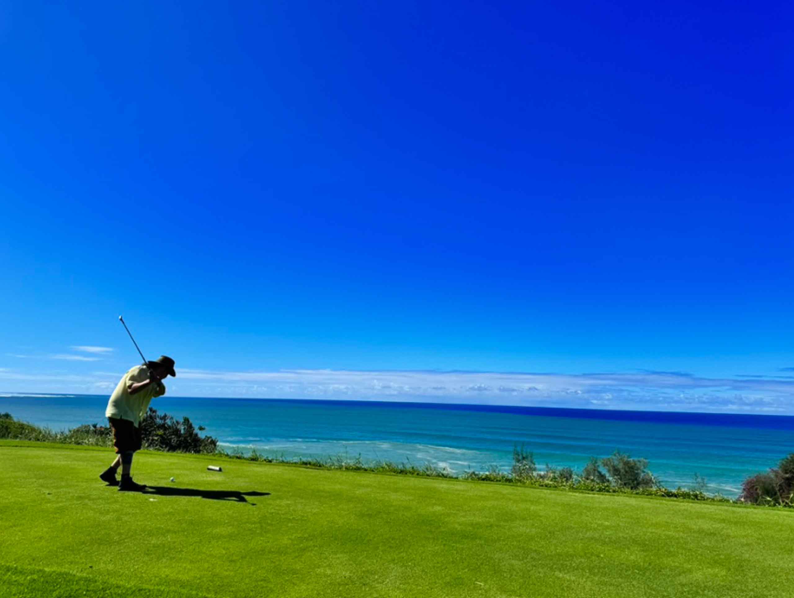 Man golfing with stunning ocean views in front of him at Princeville Makai Golf Club in Kauai, Hawaii, USA